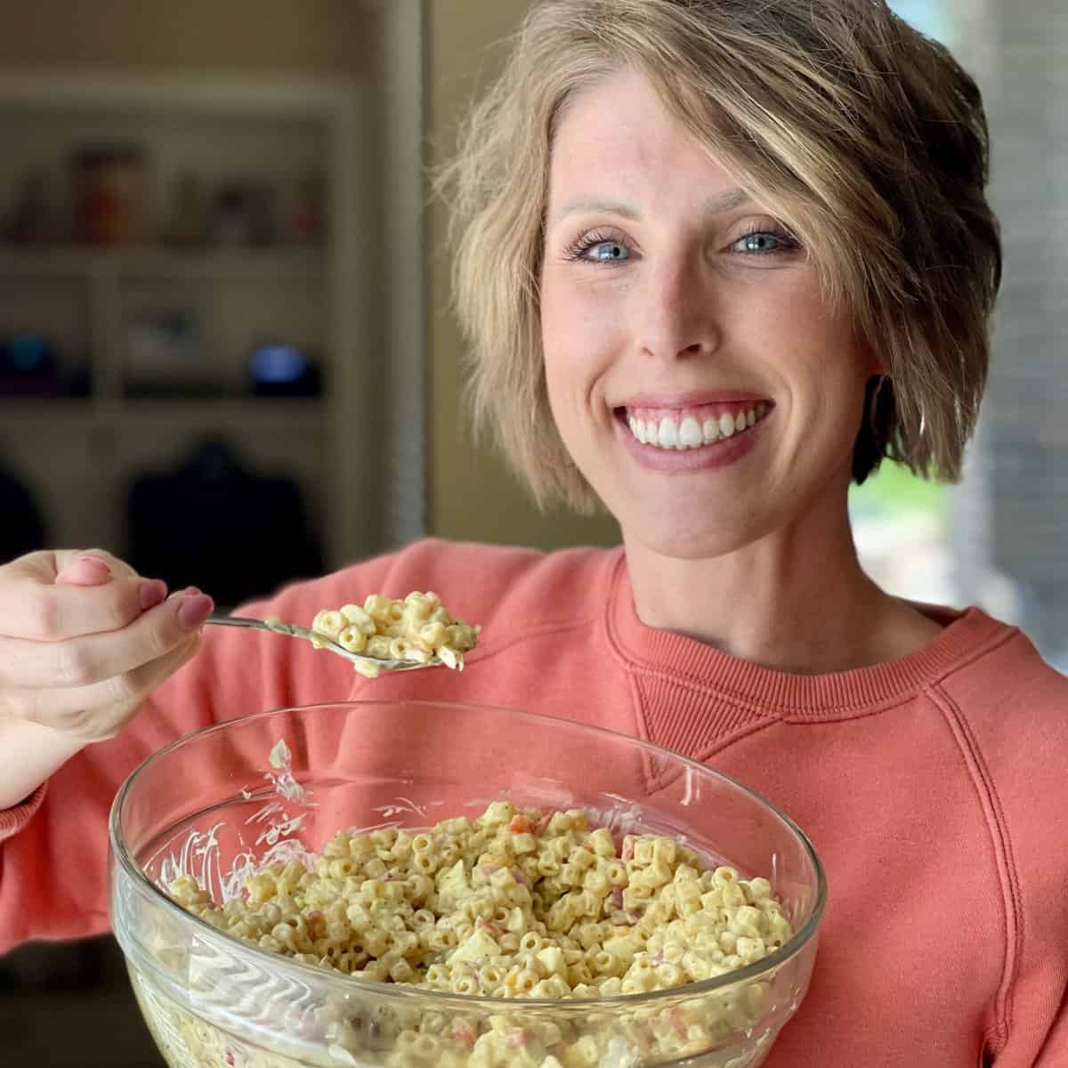 Blogger holding a bowl of macaroni salad.