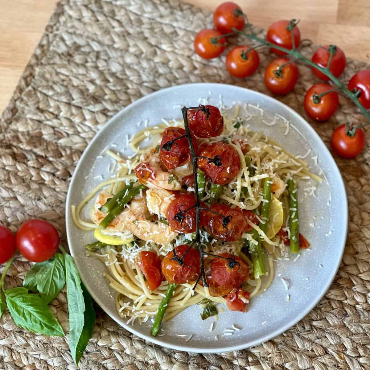 This is a picture of a plate of lemon flavored pasta. On top are roasted tomatoes and asparagus,