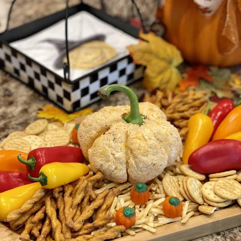 A pumpkin cheeseball on top of chips and served with pretzels and vegetables.