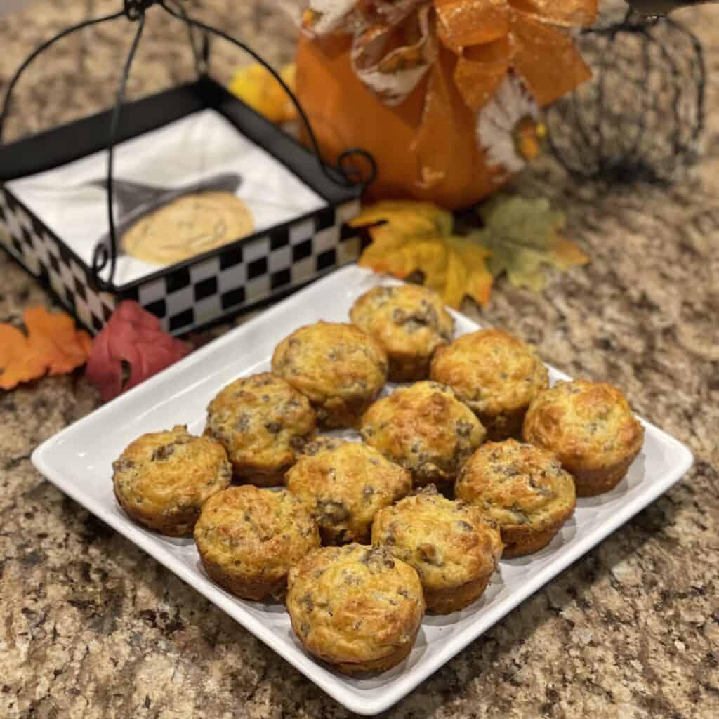 A plate full of sausage cheddar muffins with fall decor in the background.