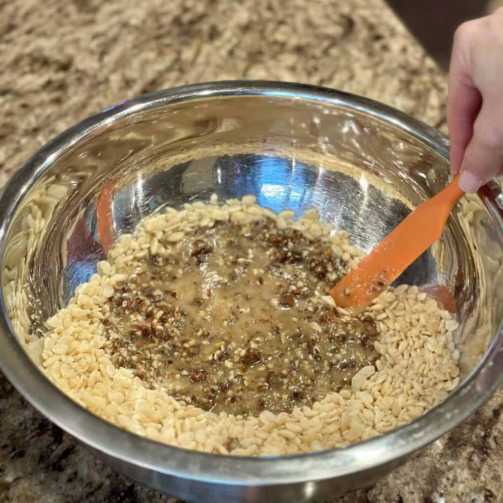 Mixing together Rice Krispies and a melted pecan date mixture.