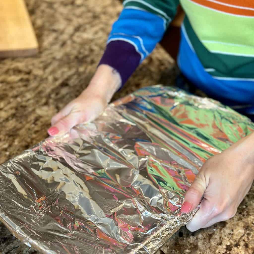 securely covering a pan of fFench onion chicken with foil