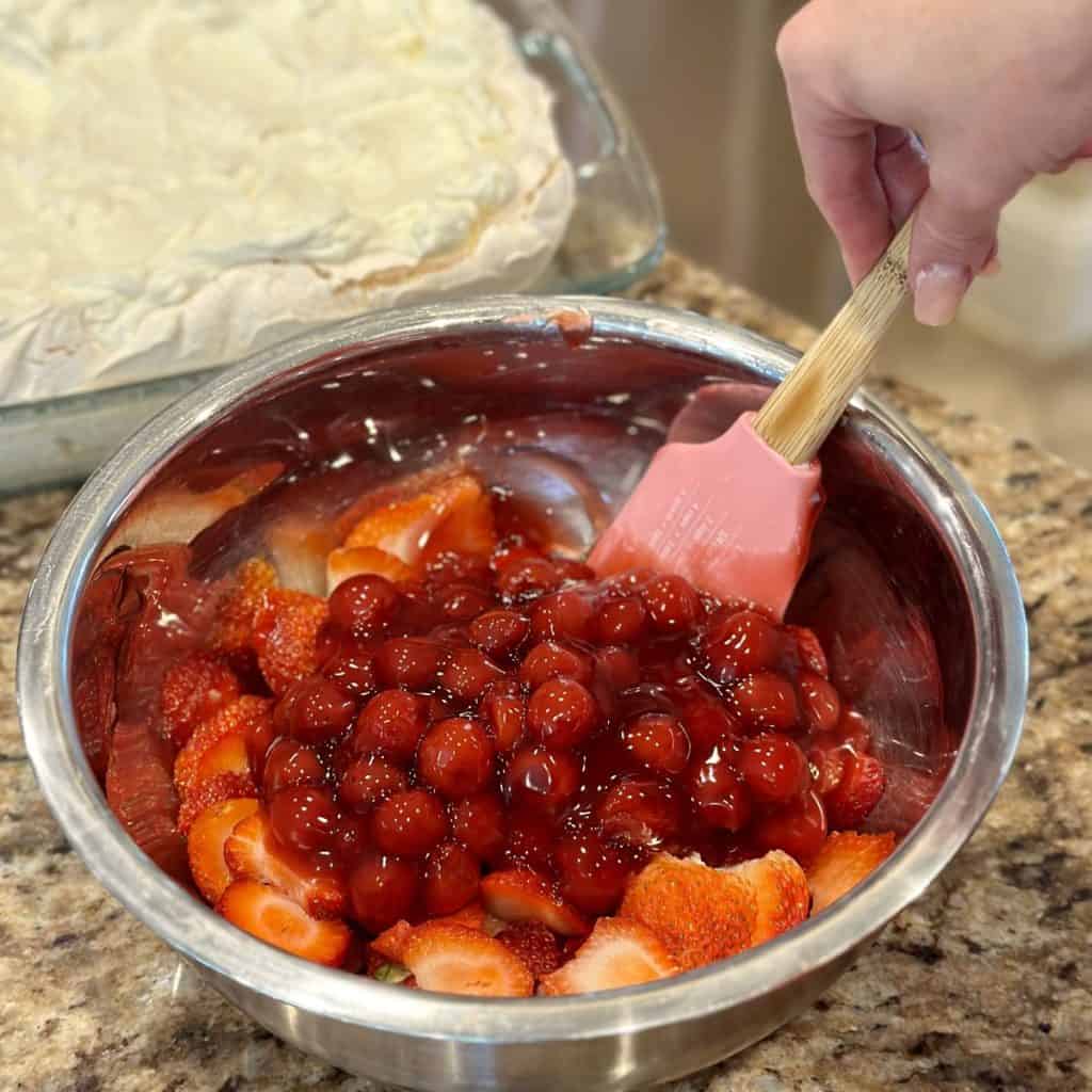 Mixing berries and cherry pie filling in a bowl.