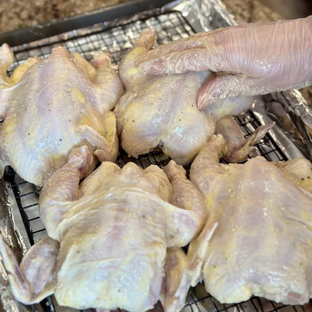 Rubbing garlic butter on Cornish game hens.