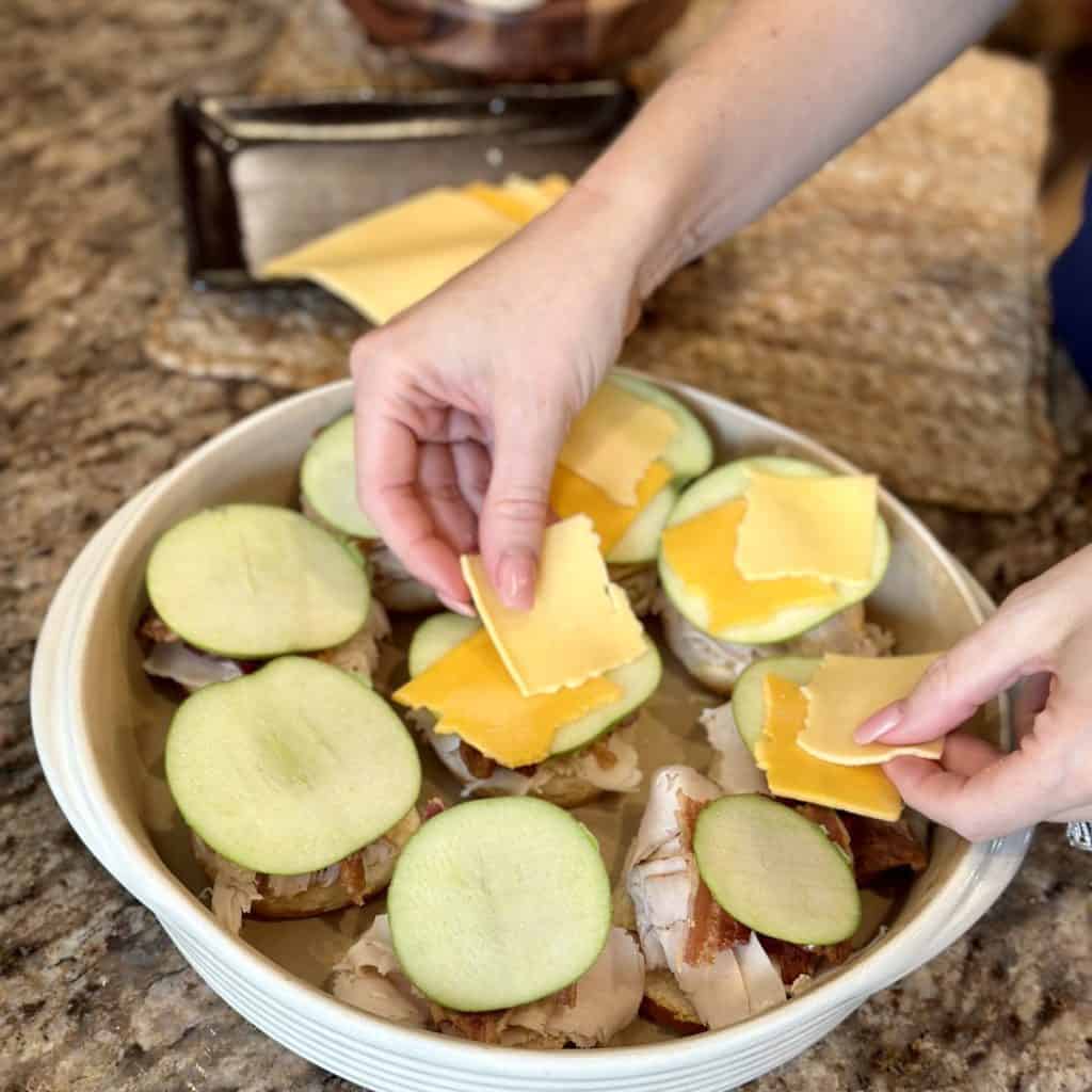 Adding cheddar slices to sandwiches.