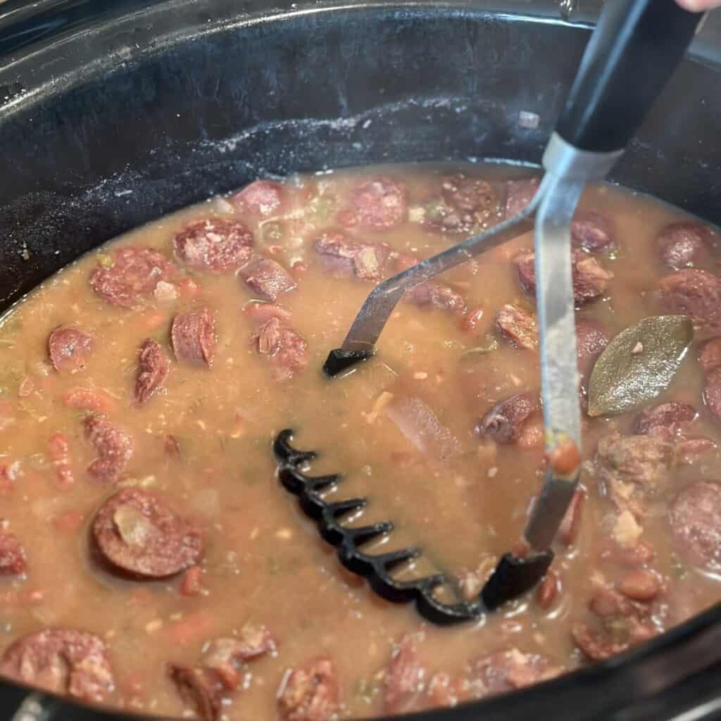 Mashing bean in a crockpot with a potato masher.