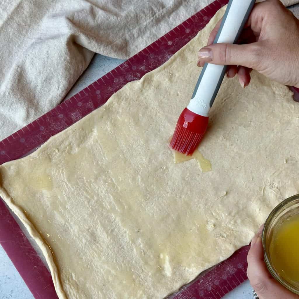 Brushing butter on crescent roll dough.