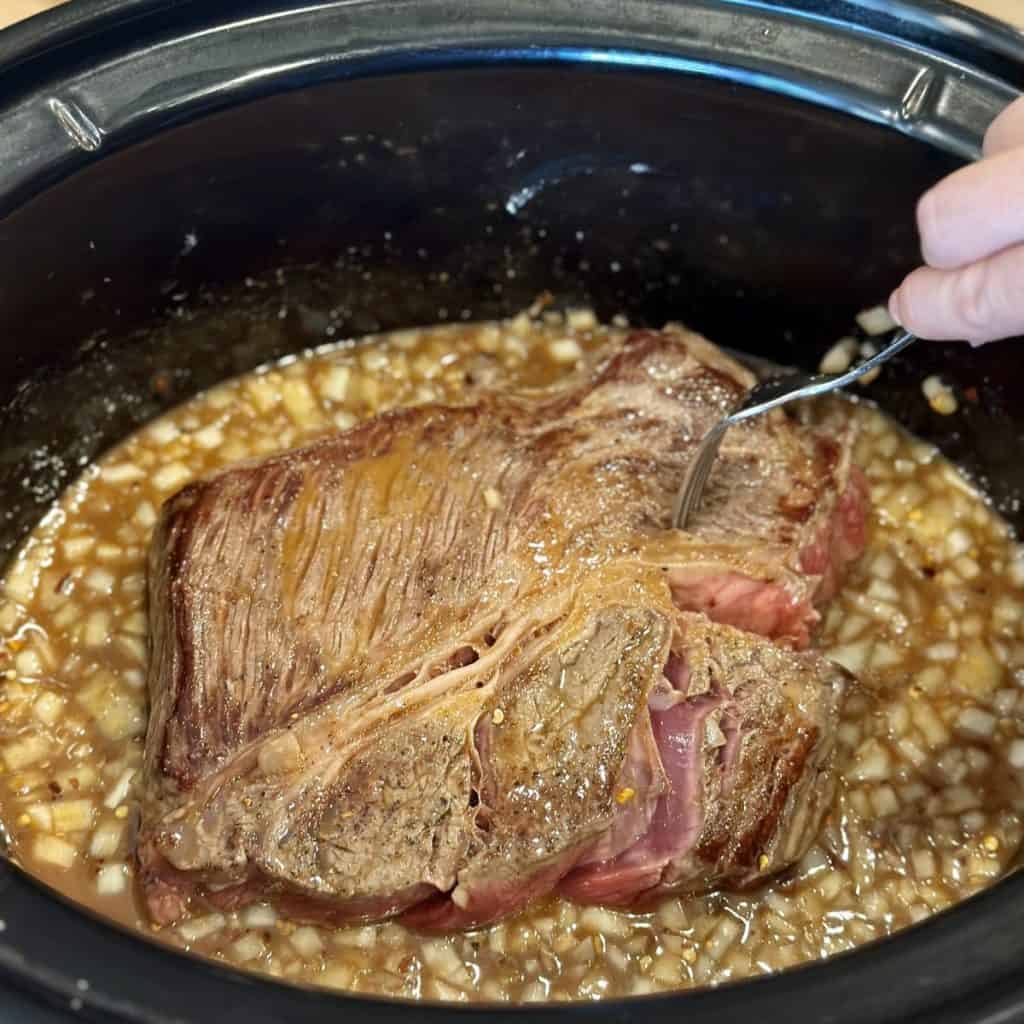 Adding a roast to a crockpot.