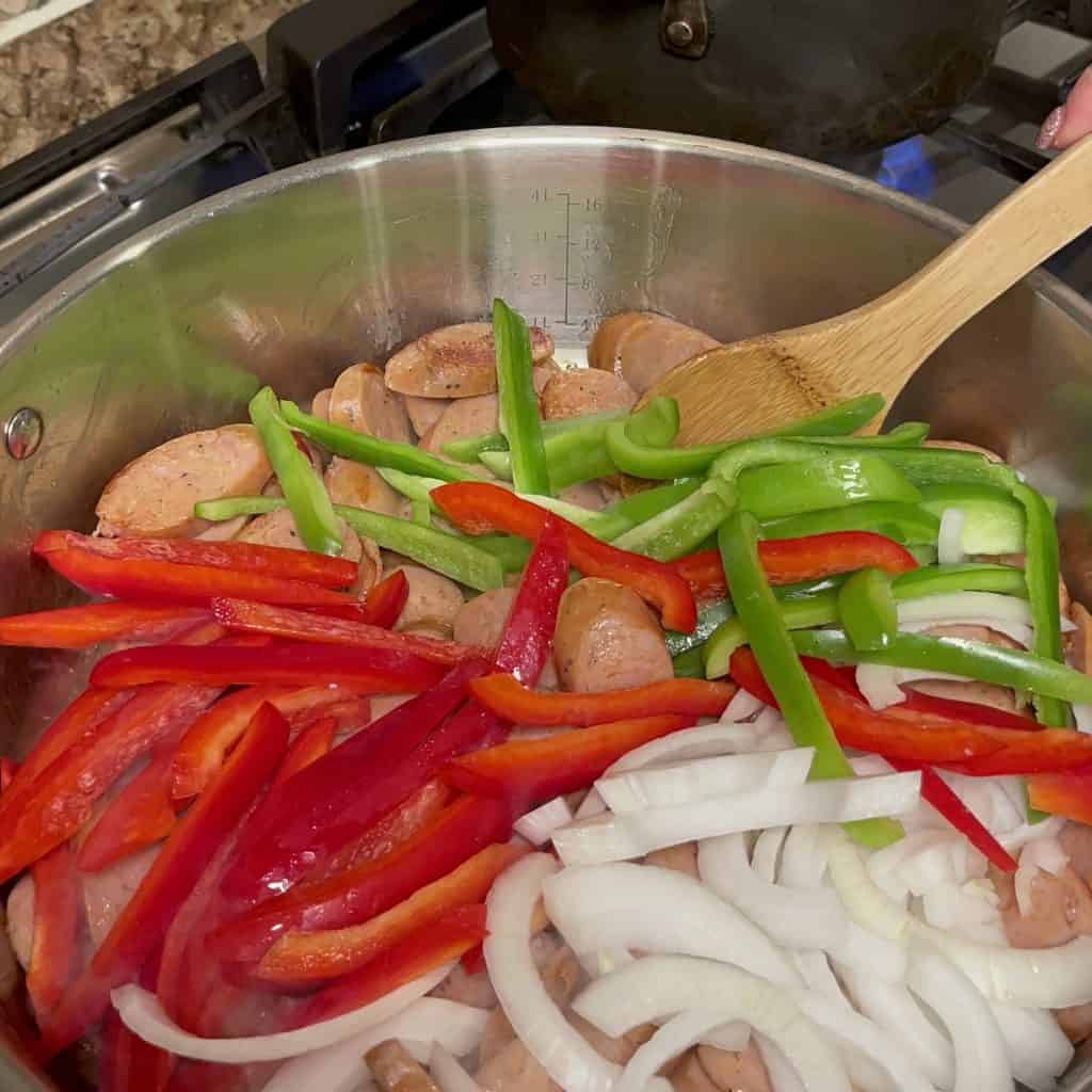 Searing sausage, peppers and onions in a skillet.