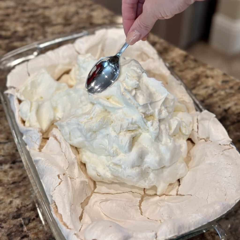 Spreading a whipped cream cheese filling in a meringue crust. 