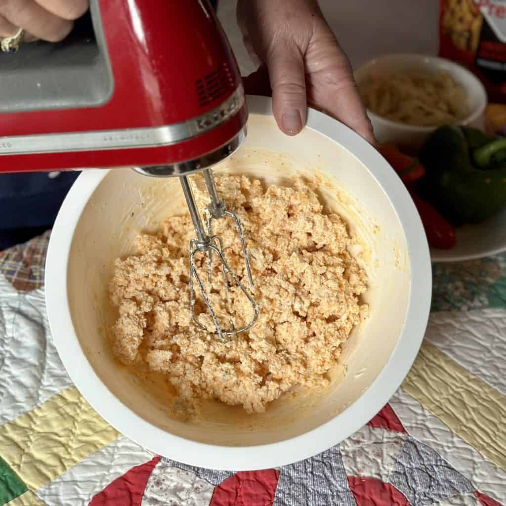 Mixing cream cheese, cheese and seasonings together for a cheeseball.