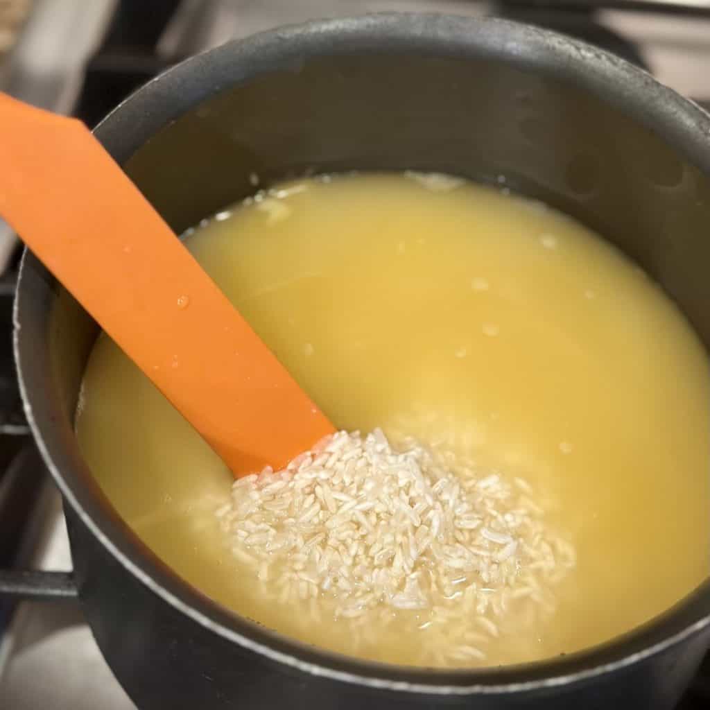 Stirring rice in a saucepan with broth.