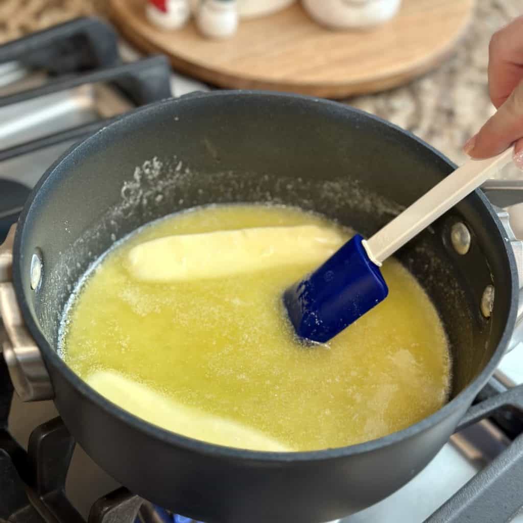 Mixing together butter and sugar in a saucepan.