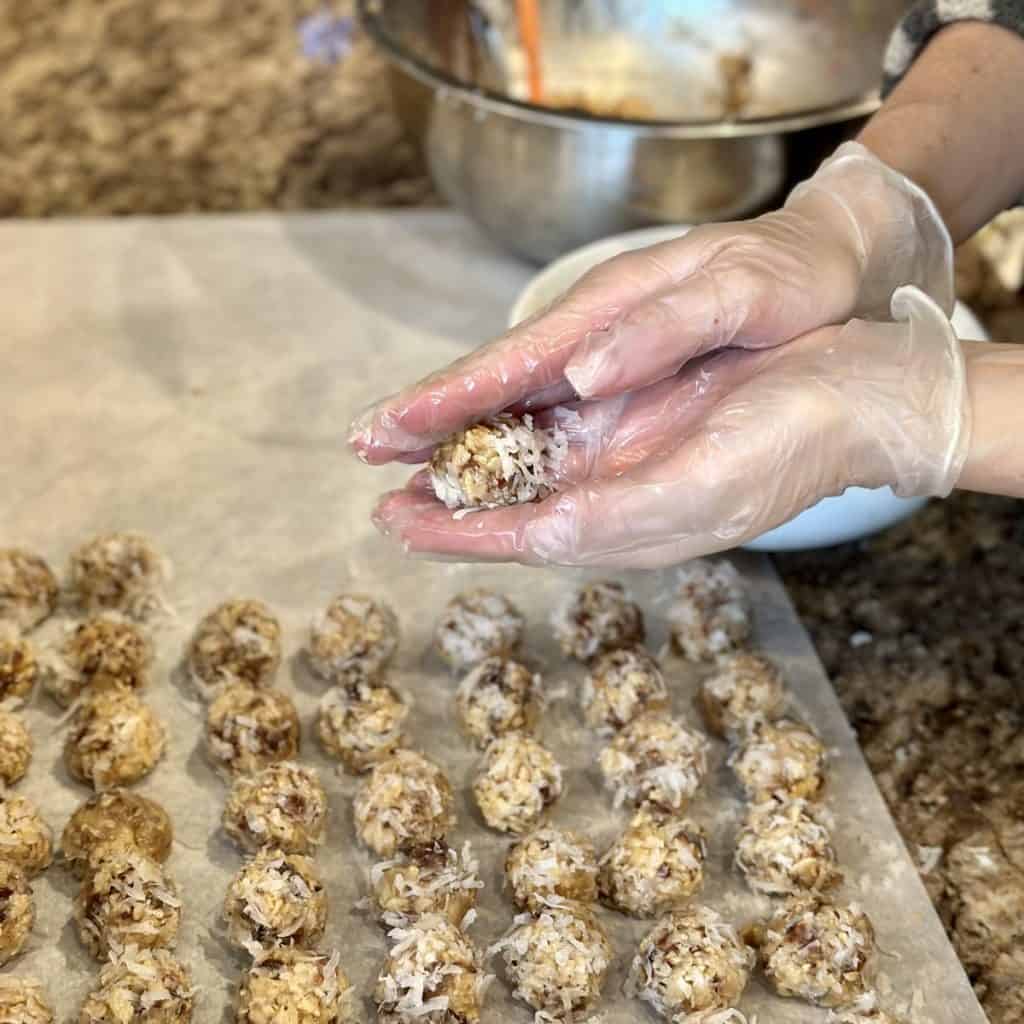 Rolling date nut balls in coconut flakes.
