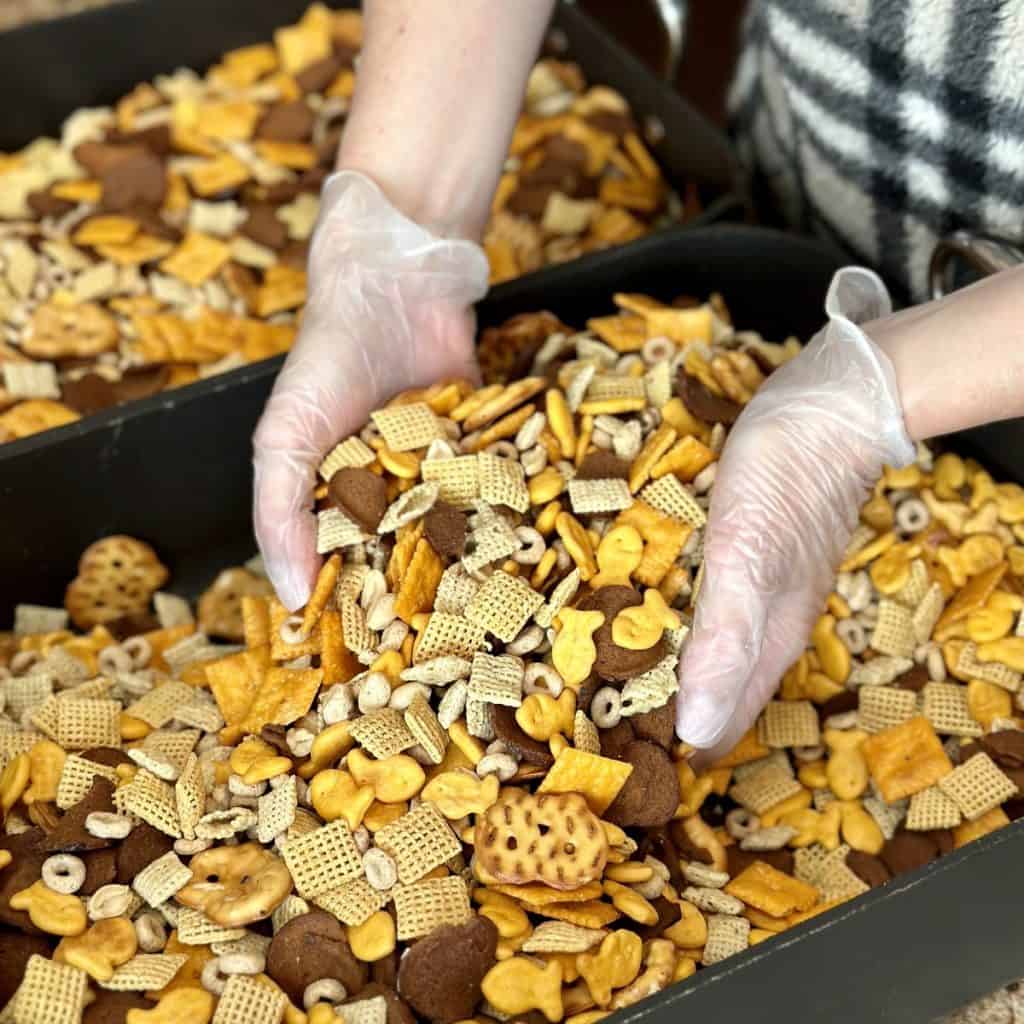 Mixing together the dry ingredients for chex mix in a roasting pan.