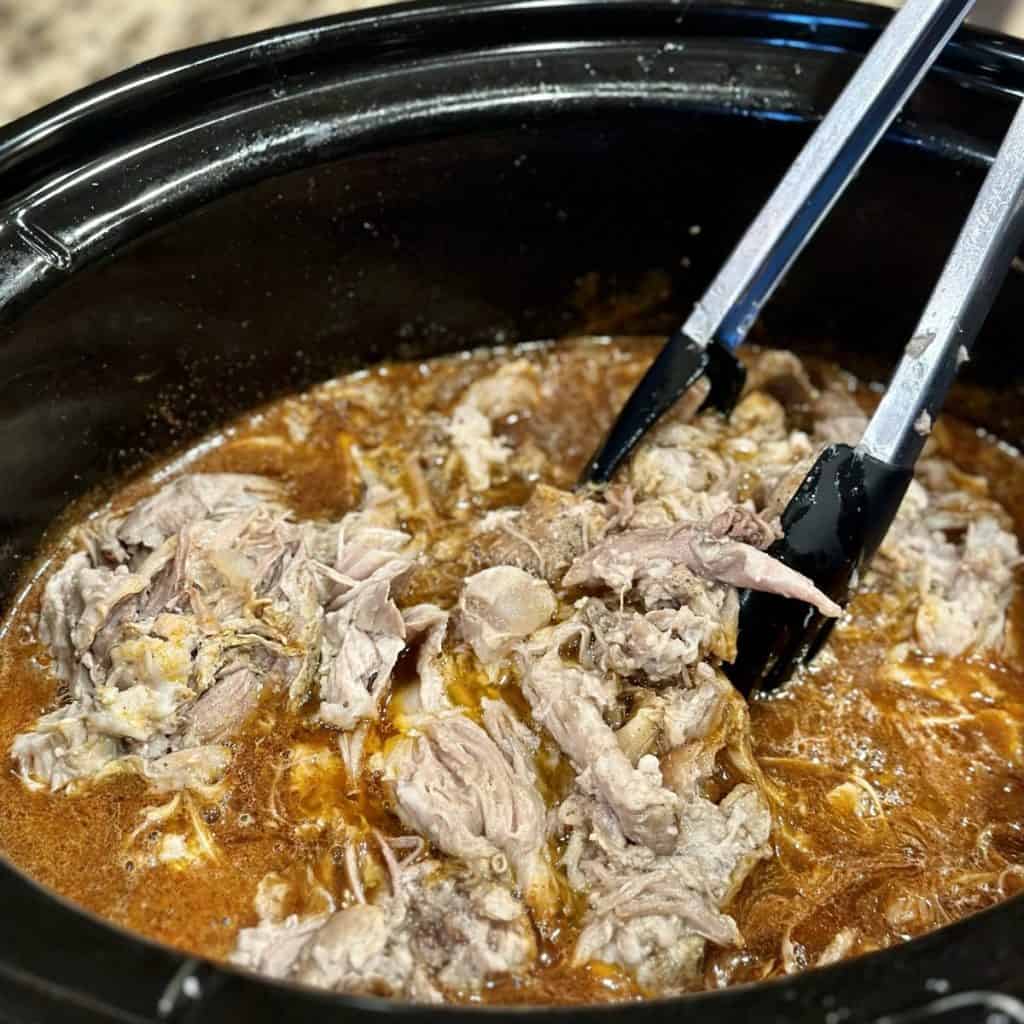 Mixing tortillas in a sweet sauce in a crockpot.