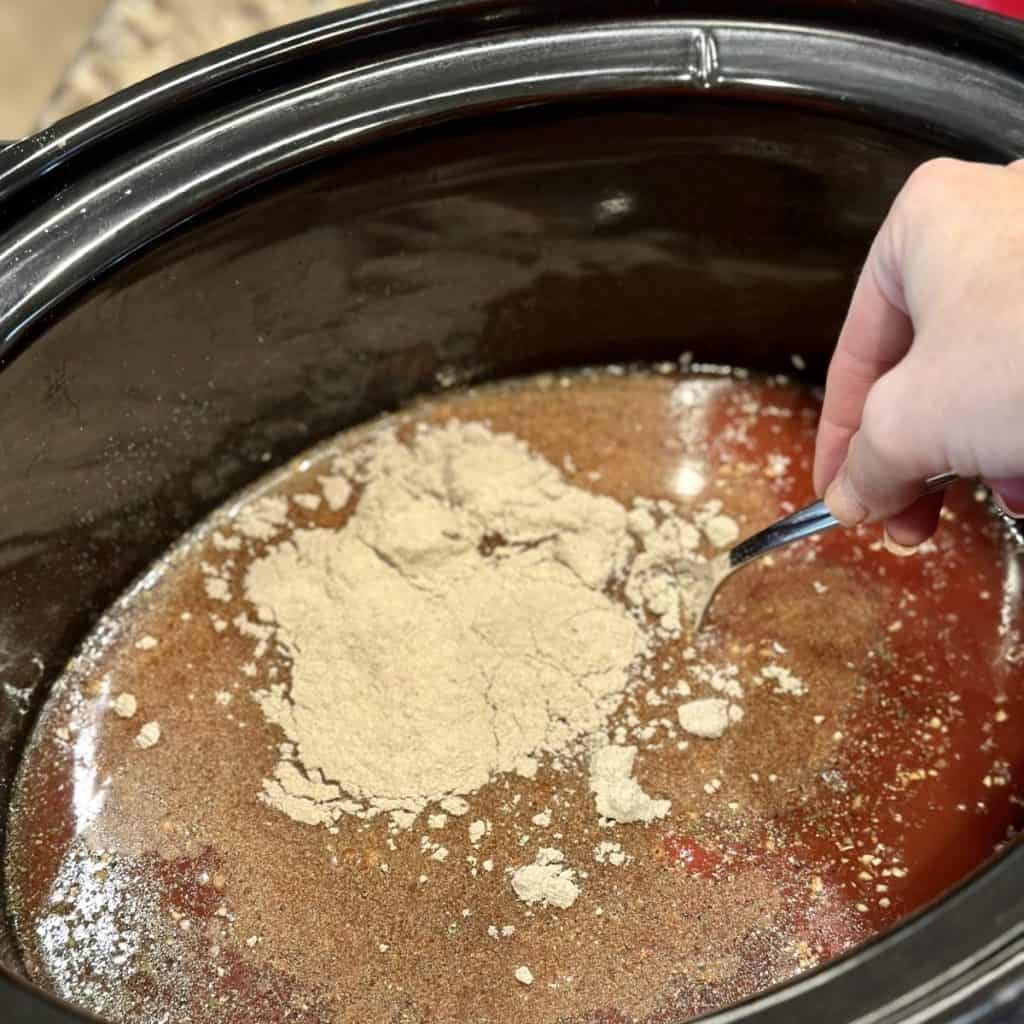 Mixing together the sauce ingredients in a crockpot for an Italian roast beef.