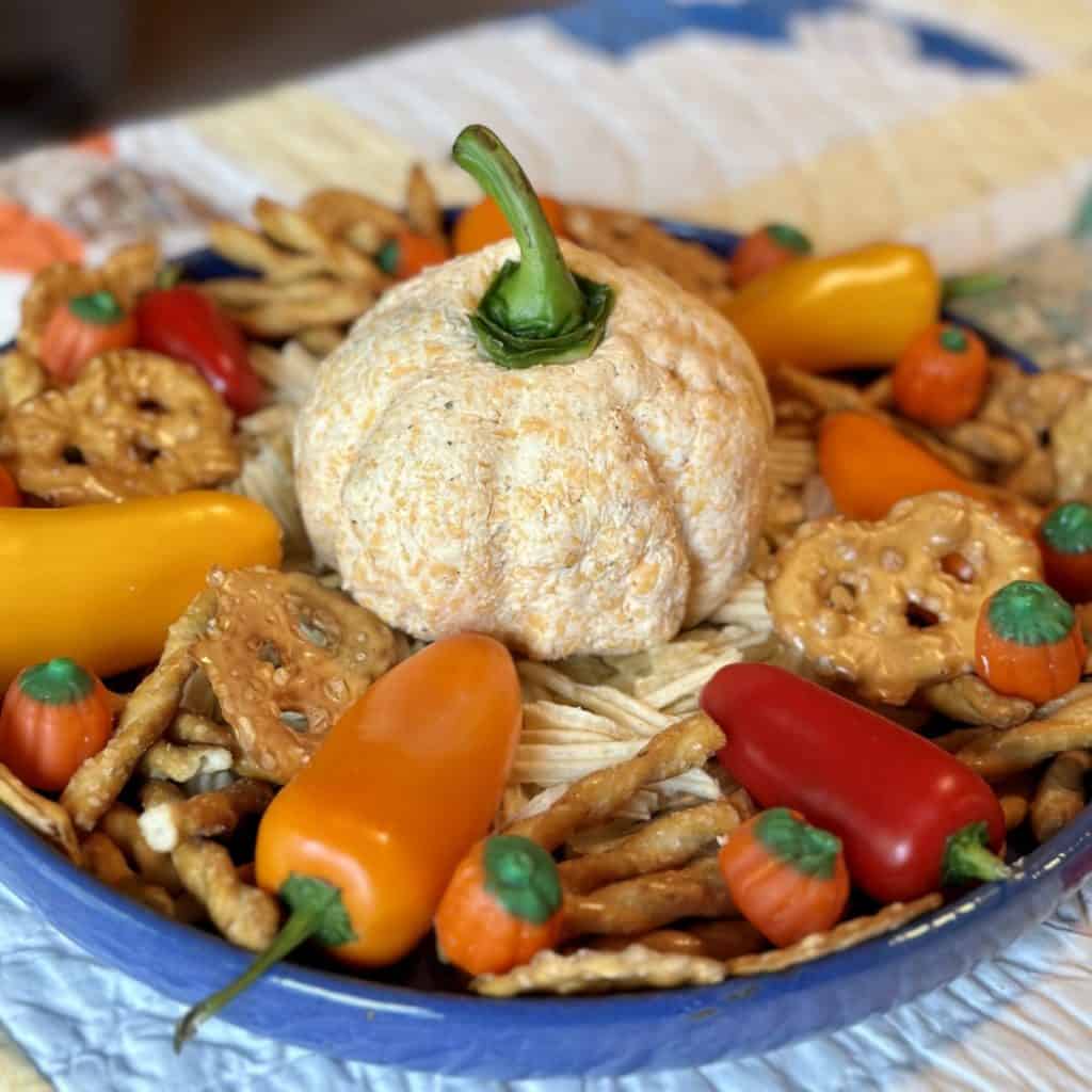 A pumpkin cream cheese ball in the center of chips and vegetables.