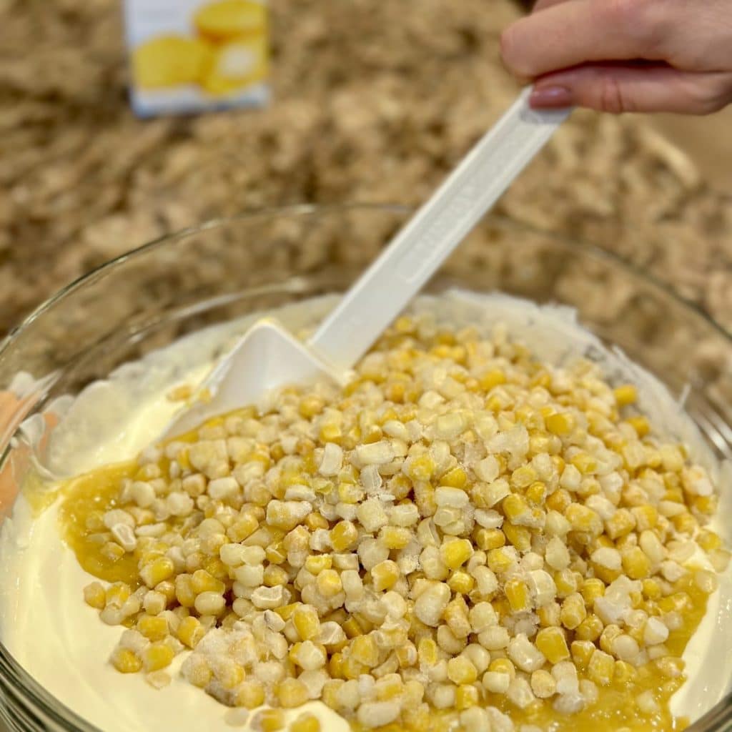 Bowl of ingredients for country scalloped corn including eggs, cream style corn, corn and sour cream.