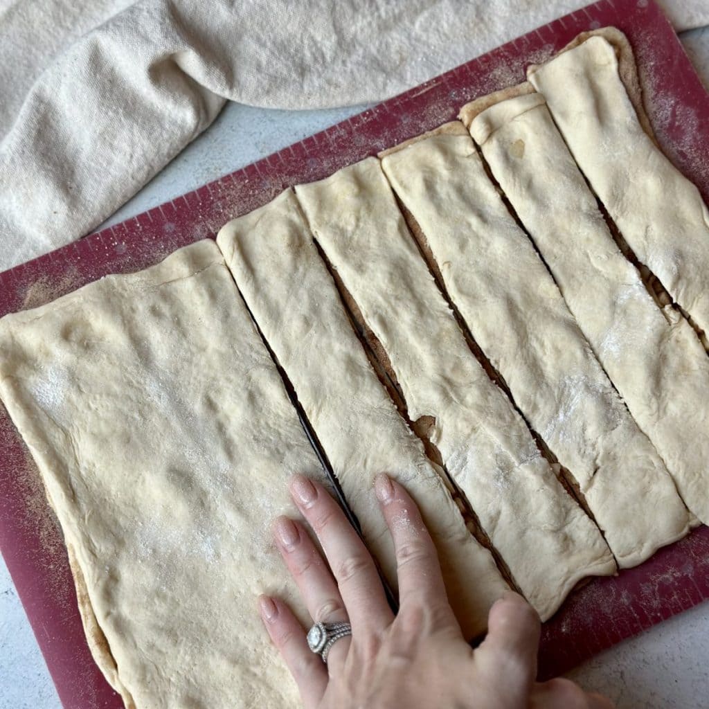Slicing dough into cinnamon rolls.