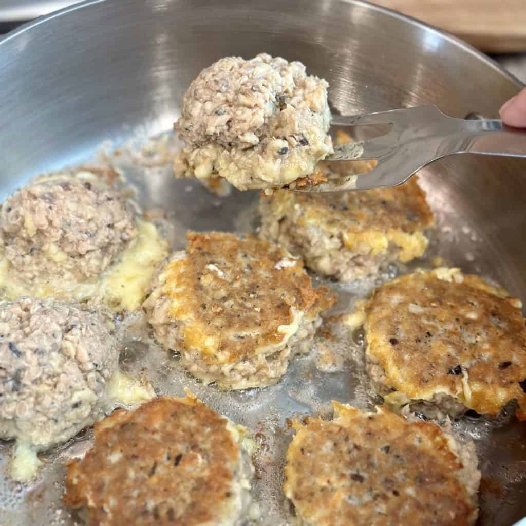 Flipping salmon patties in a skillet.