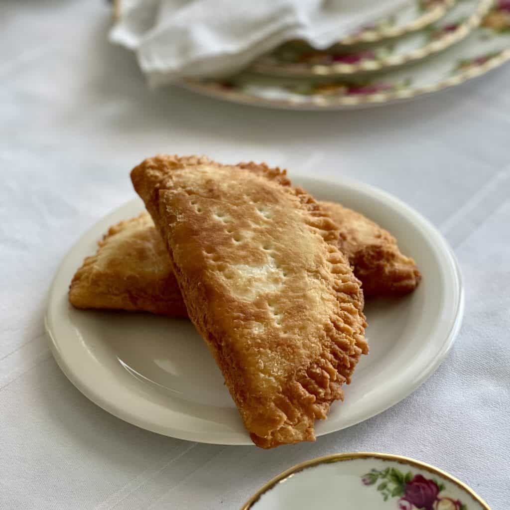 This is a picture of golden brown fried apples pies laying on a saucer. 