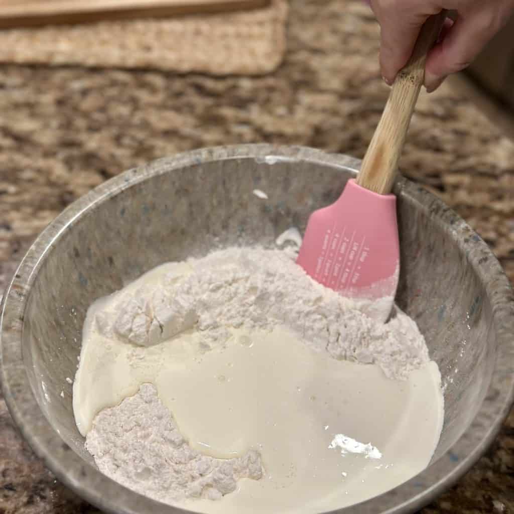 Mixing together whipping cream and flour in a bowl.
