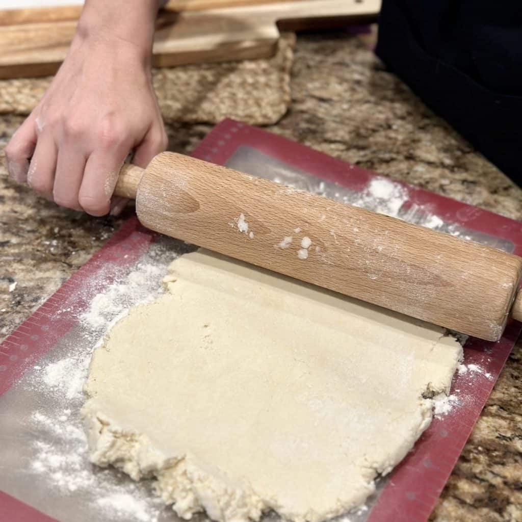 Rolling biscuit dough with a rolling pin.