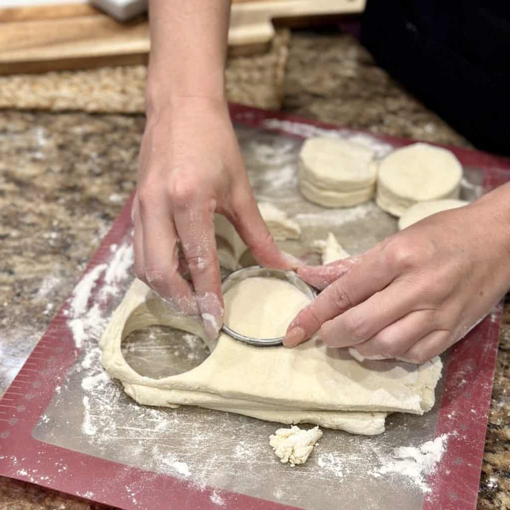 Cutting out biscuit dough with a biscuit cutter.