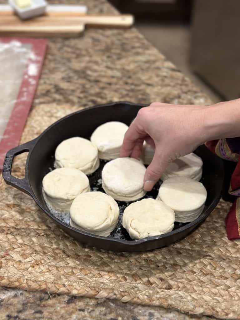 Placing biscuit dough in a cast iron skillet.