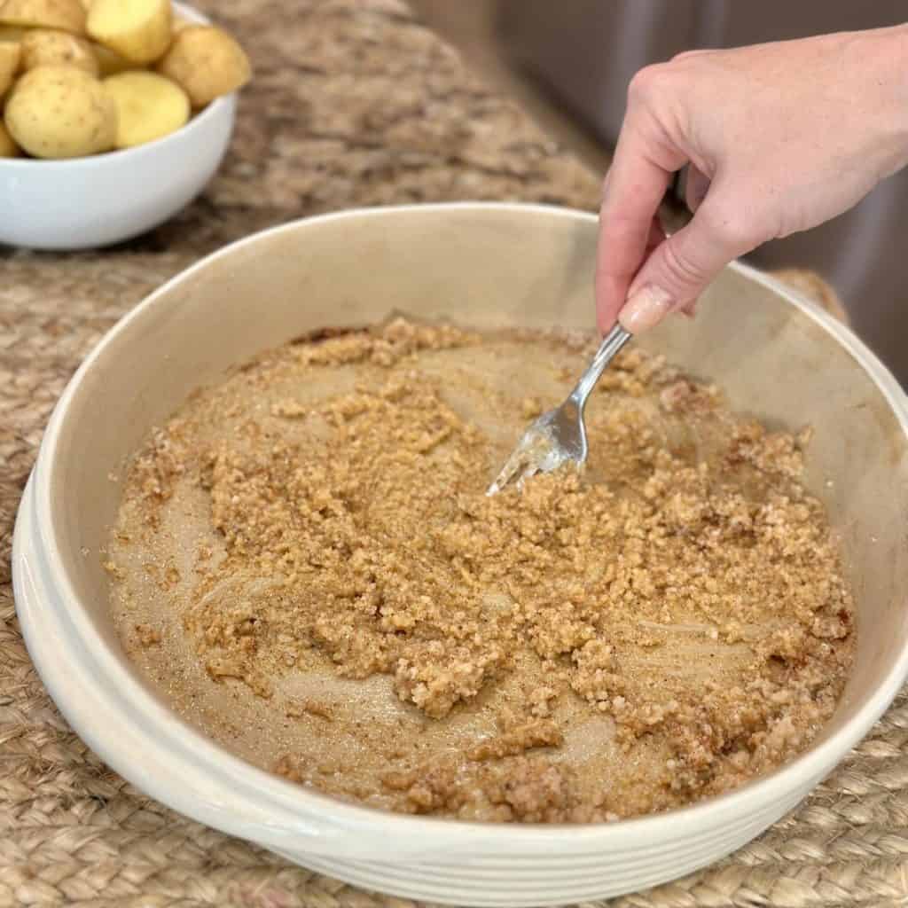 Mixing together a cheesy paste in a dish for potatoes.