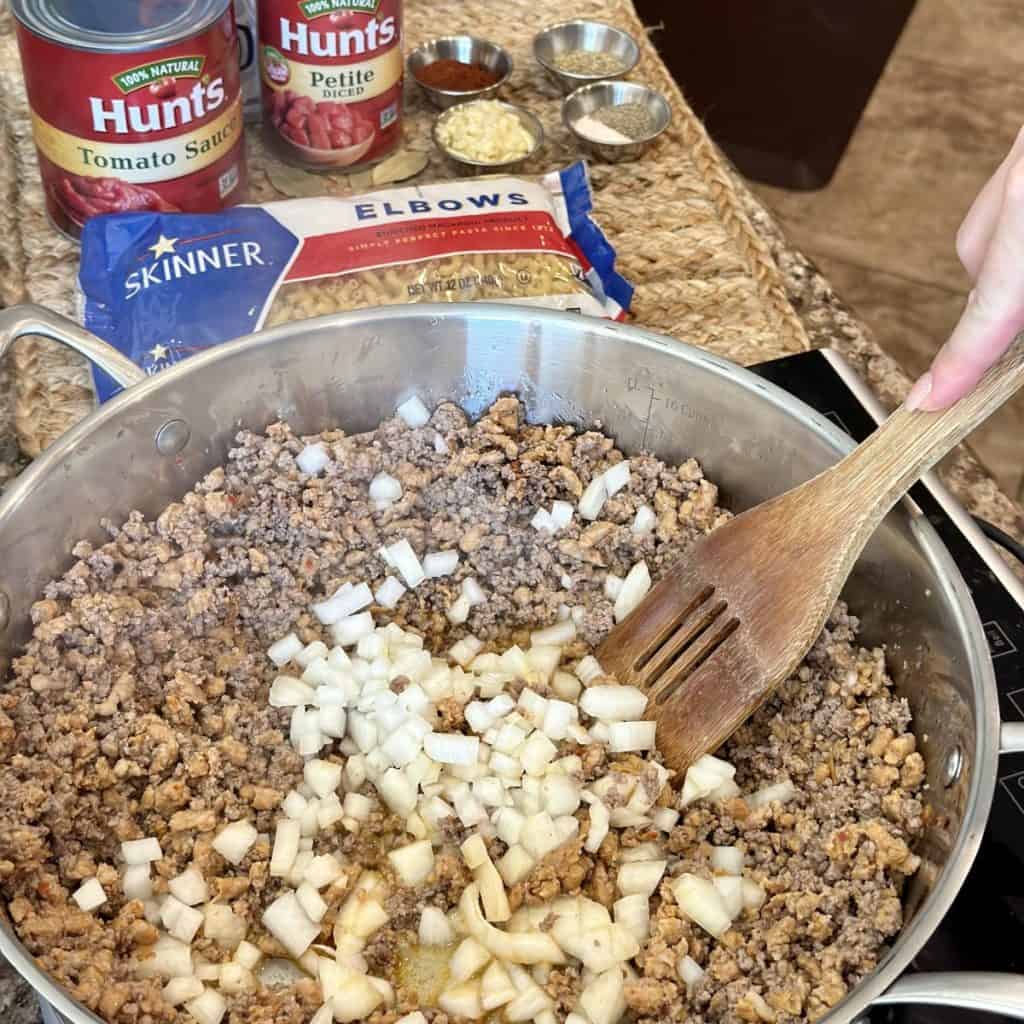 Browning onion and ground beef and sausage in a skillet.