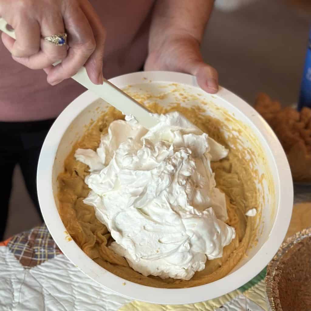 Folding whipped cream in a spiced pumpkin pie.