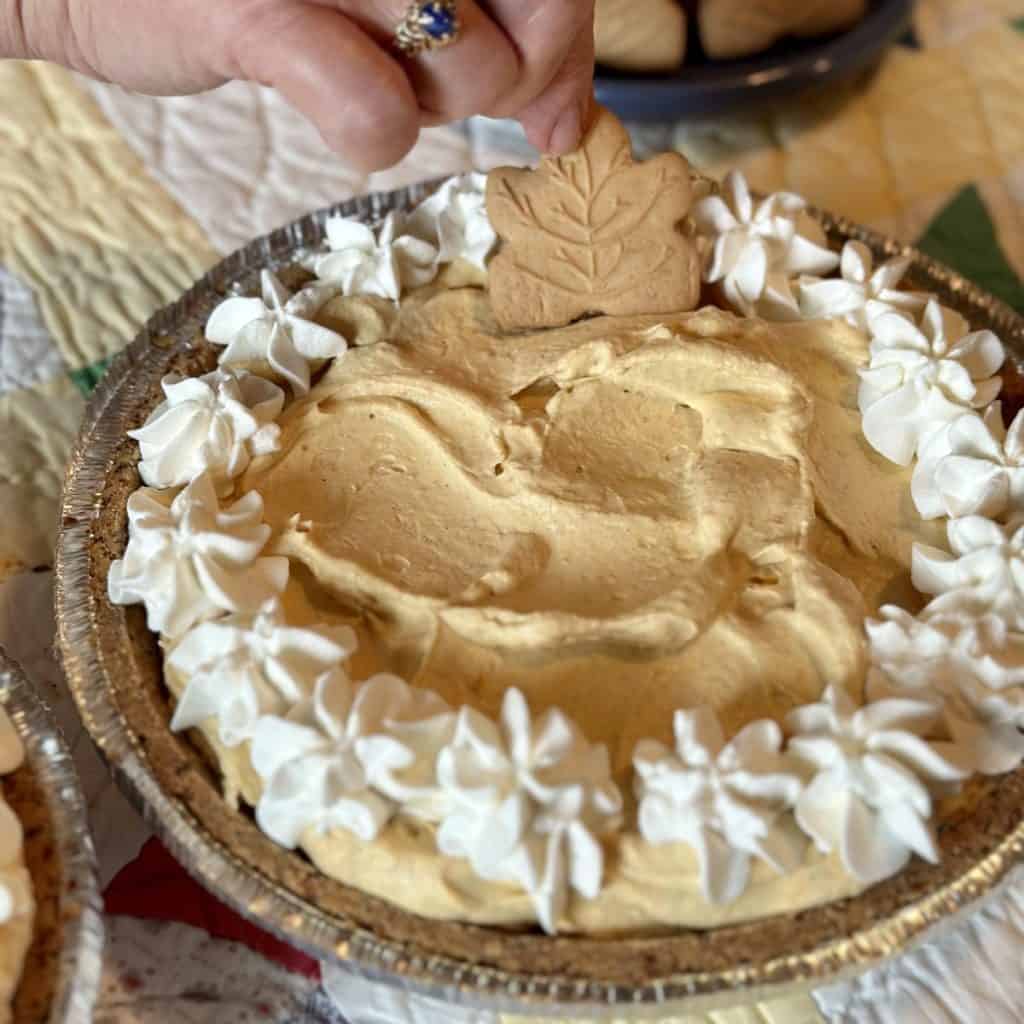 Adding a maple cookie to the top of a pumpkin pie.