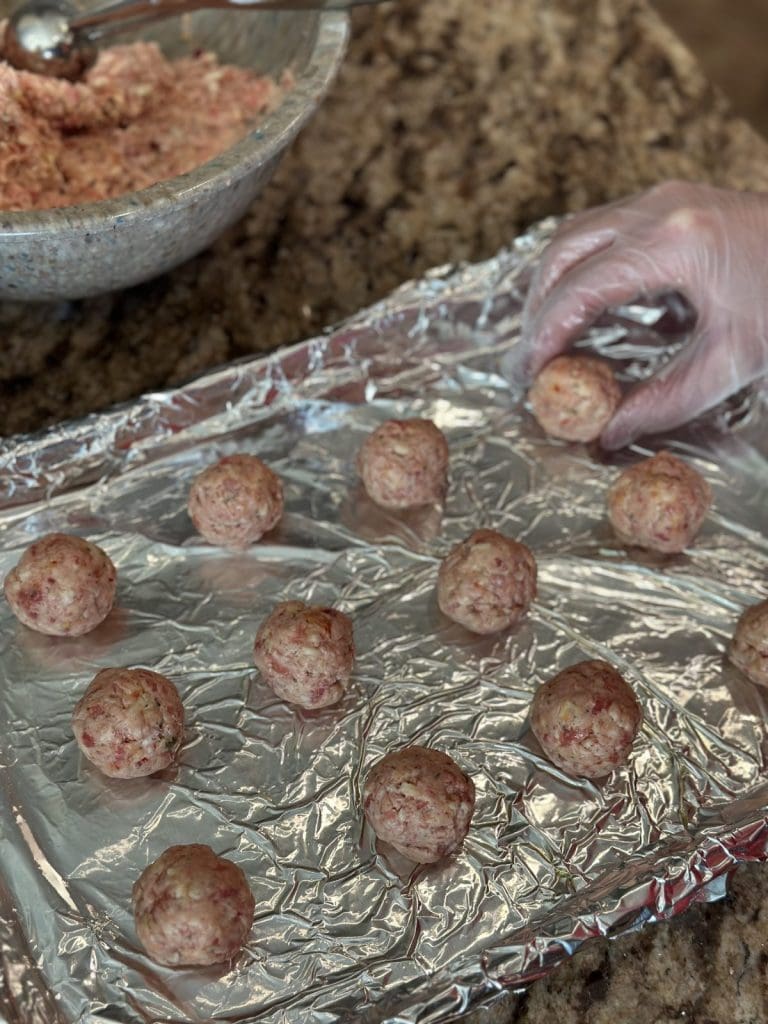 Placing sausage balls on a sheet pan.
