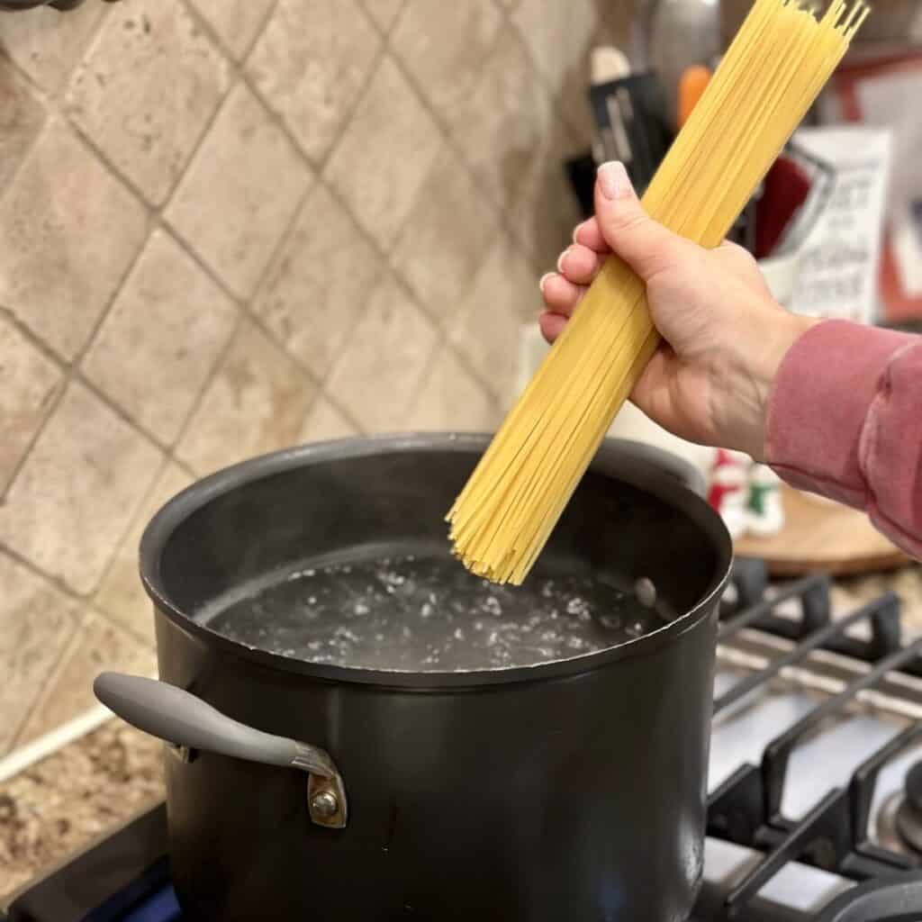 Adding pasta to a pot of water.