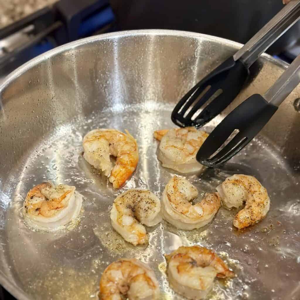 Searing shrimp in a skillet.