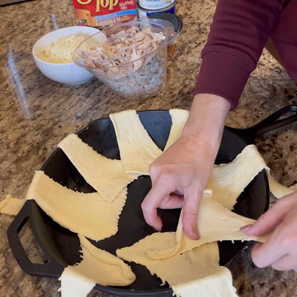 Laying crescent rolls in a cast iron skillet.
