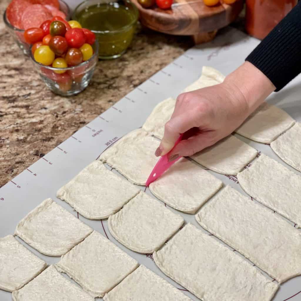 Cutting pizza dough into squares.