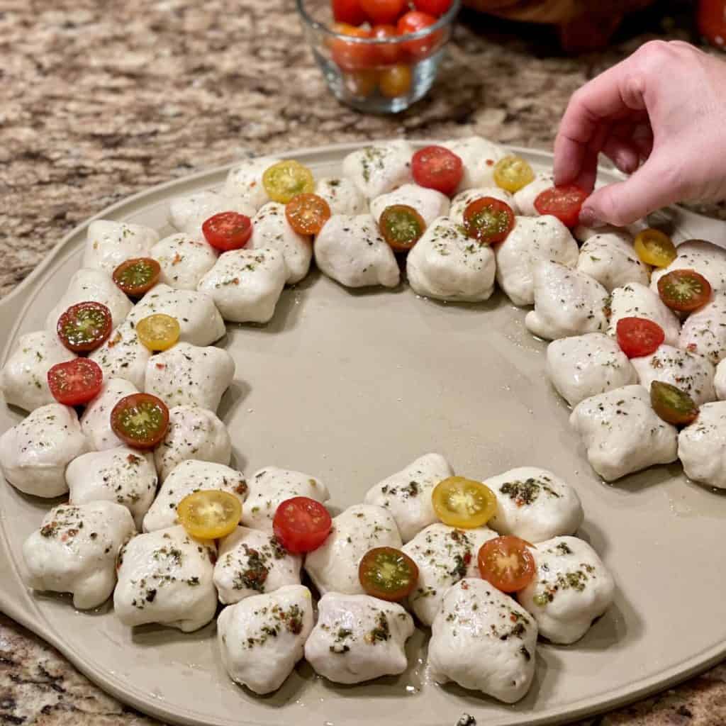 Laying halved tomatoes on pizze rolls.