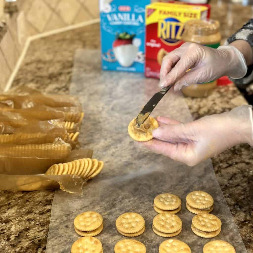 Spreading peanut butter on crackers.