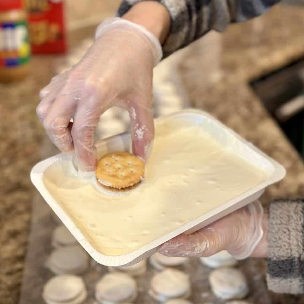 Dipping peanut butter and crackers into vanilla candy coating.