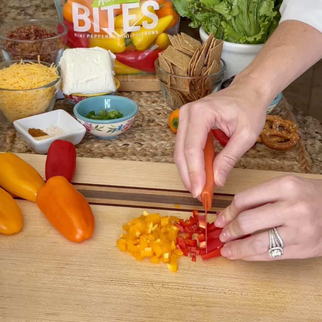 Dicing many sweet peppers on a cutting board.