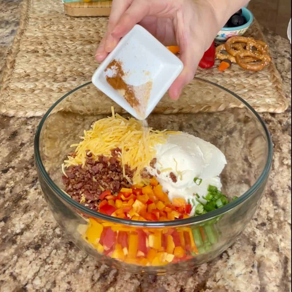 Mixing together cheeseball ingredients in a bowl.