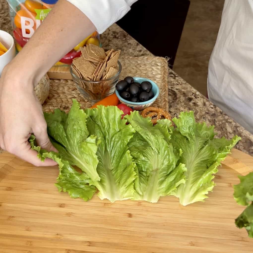 Lettuce leaves being added to a vegetable Cheeseball board.