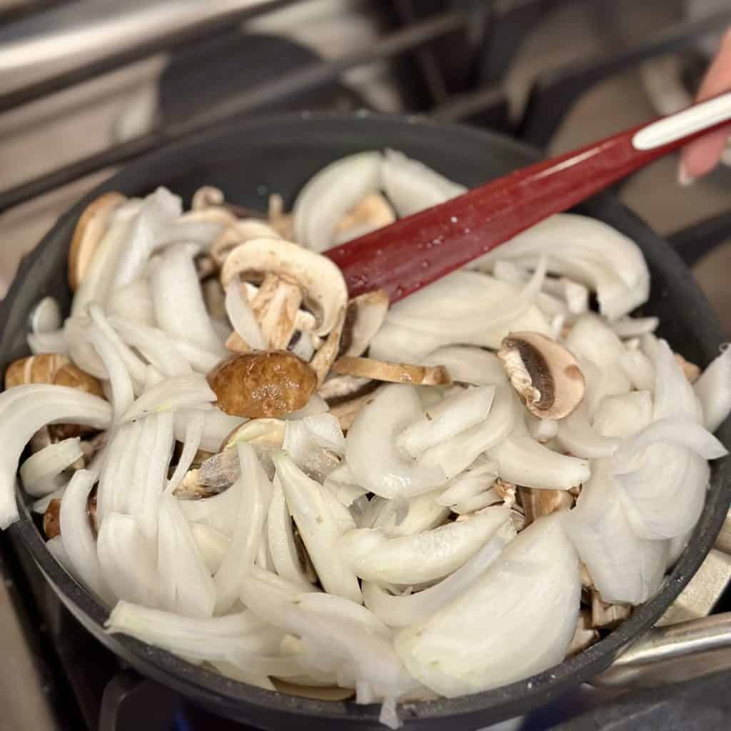 Sautéing mushrooms and onions in a skillet.