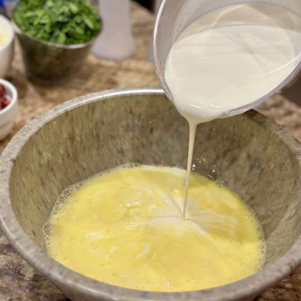 Pouring whipping cream into eggs in a bowl.