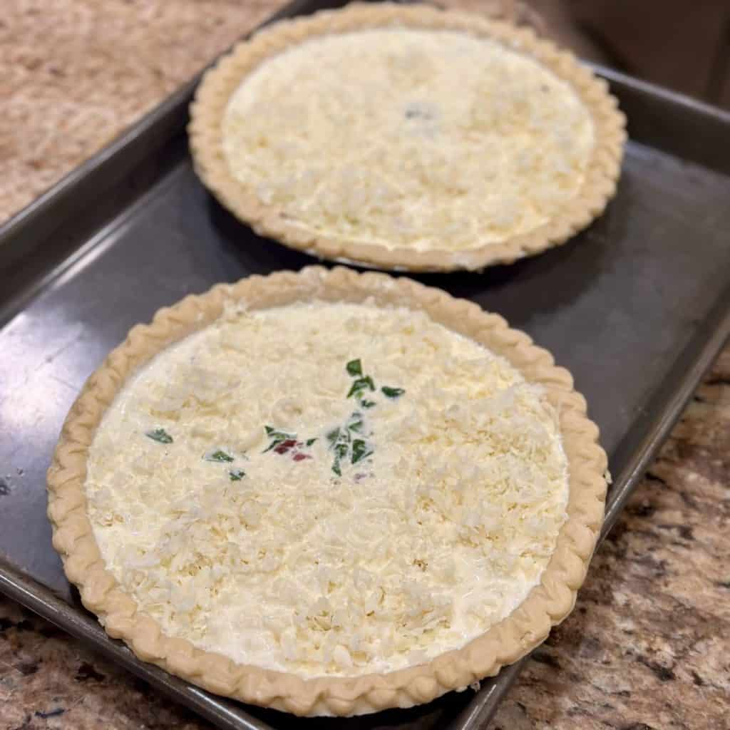 To quiche ready to be baked on a cookie sheet.