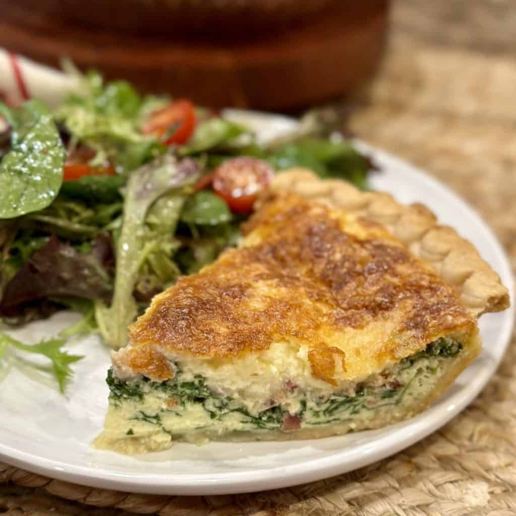 A slice of quiche on a plate.