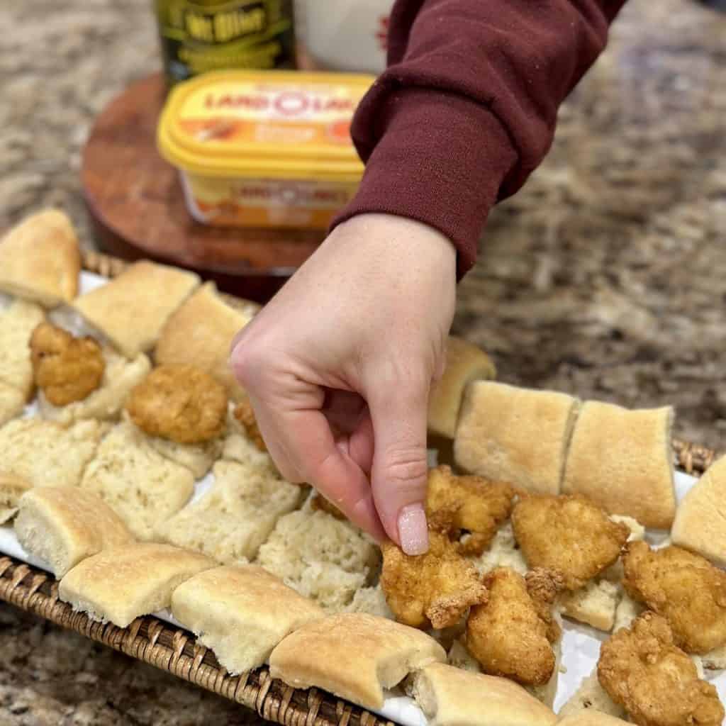 Placing cooked chicken on rolls.